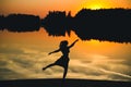 Silhouette of a young beautiful girl in a jump on a background of a sunset in reflection pond Royalty Free Stock Photo