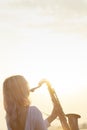 Silhouette of a young beautiful girl playing the saxophone at sunrise by the river, a woman in a long dress on the nature at