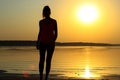 Silhouette of a young beautiful girl walking along the seashore during orange sunset Royalty Free Stock Photo