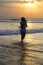 Silhouette of young beautiful and asian woman running free and happy having fun at sunset beach in Bali Royalty Free Stock Photo