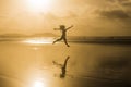 Silhouette of a young beautiful woman jumping at the beach by the shore. Sunset. Yellow sky. Lanzarote, Canary islands Royalty Free Stock Photo