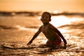 Silhouette of young boy playing crazy happy and free at the beach splashing with water playing with sea waves jumping and having Royalty Free Stock Photo