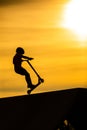 Silhouette of a young  boy riding a scooter Royalty Free Stock Photo