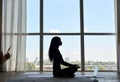 Silhouette of young calm fit black woman at home learning yoga online class.