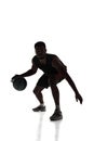 Silhouette of young concentrated young man, basketball player in motion during game, dribbling ball isolated on white Royalty Free Stock Photo