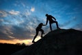 Silhouette of young couple hand helping with amazing heaven on background. Rock climbing at the dawn.