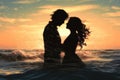 Silhouette of a young couple kissing in the sea at sunset, Silhouette of a couple in love emerging from the ocean, a summer