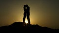 Silhouette of young couple in love hugging, kissing in sunset rays on mountain Royalty Free Stock Photo
