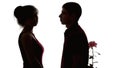 Silhouette of a young couple in love on white isolated background, man brought flower to offended girl to make amends, concept of Royalty Free Stock Photo