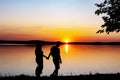 Silhouette of young couple, man and girl, who are watching sunset on shore. Sun setting over horizon Royalty Free Stock Photo