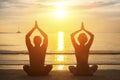 Silhouette of young couple practicing yoga on the beach. Royalty Free Stock Photo
