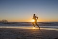 Silhouette young dynamic athlete runner man with fit strong body training on Summer sunset beach running barefoot in sport healthy Royalty Free Stock Photo