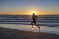 Silhouette young dynamic athlete runner man with fit strong body training on Summer sunset beach running barefoot in sport healthy Royalty Free Stock Photo