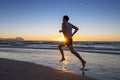 Silhouette young dynamic athlete runner man with fit strong body training on Summer sunset beach running barefoot in sport healthy Royalty Free Stock Photo