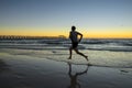 Silhouette young dynamic athlete runner man with fit strong body training on Summer sunset beach running barefoot in sport healthy Royalty Free Stock Photo