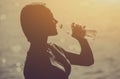 Silhouette of a young female athlete in tracksuit drinking water from a bottle Royalty Free Stock Photo