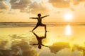 Silhouette of young fit and healthy attractive woman practicing fitness and yoga in beautiful sunset beach in meditation and relax Royalty Free Stock Photo