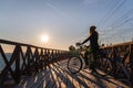 Silhouette of young girl with a bicycle standing on wooden bridge at the sunset Royalty Free Stock Photo