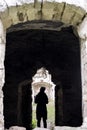 Silhouette of a young girl in the doorway of a dilapidated ancient synagogue.View through an arched window. Rashkov, Moldova. Royalty Free Stock Photo