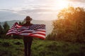 Silhouette of young girl in hat holding American Flag looking out at landscape. Patriotic american woman 20s old years enjoying Royalty Free Stock Photo