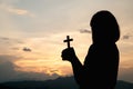 Silhouette of a young girl holding a crucifix to God Morning with beautiful sunrise, Symbol of Faith. Christian life prayer crisis Royalty Free Stock Photo