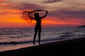 Silhouette of young girl, jumping with silk cloth against of sea sunset Royalty Free Stock Photo