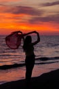 Silhouette of young girl, jumping with silk cloth against of sea sunset Royalty Free Stock Photo