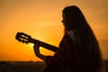 Silhouette of young girl playing the guitar at sunset Royalty Free Stock Photo