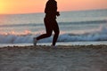 Silhouette of a young girl running alone along the beach of the Royalty Free Stock Photo