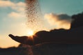 Silhouette of a young girl`s hand pouring sand from a beach against a blue sky at sunset Royalty Free Stock Photo