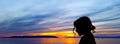 Silhouette of a young girl with sunset over the Adriatic Sea in background in Makarska, Croatia Royalty Free Stock Photo