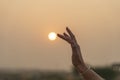 Silhouette of a young girl touching the sun with her hand during sunset Royalty Free Stock Photo