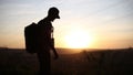 Silhouette of young guy on a hiking, using laptop for searching coordinates.