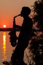 Silhouette of a young guy playing the saxophone in the evening at sunset Royalty Free Stock Photo