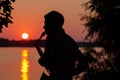Silhouette of a young guy playing the saxophone in the evening at sunset Royalty Free Stock Photo