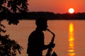 Silhouette of a young guy playing the saxophone in the evening at sunset Royalty Free Stock Photo