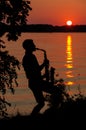 Silhouette of a young guy playing the saxophone in the evening at sunset Royalty Free Stock Photo