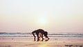 Silhouette of young gymnast woman doing handspring on sandy beach