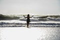 Silhouette of young happy Asian woman relaxed looking at wild sea waves on sunset tropical beach Royalty Free Stock Photo