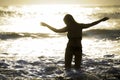 Silhouette of young happy Asian woman relaxed looking at wild sea waves on sunset tropical beach Royalty Free Stock Photo