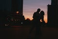 Silhouette of young happy couple in love dancing on city street at sunset Royalty Free Stock Photo