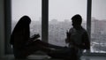 Silhouette of a young happy couple sitting on the window in front of snowy winter day