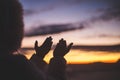 Silhouette of young human hands open palm up worship and praying to god at sunrise, Christian Religion concept background