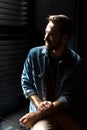 Silhouette of young joyful man standing in dark room at shadow blinds