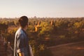 Silhouette of young male backpacker watching sunset and pagoda in Bagan, Burma.