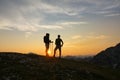 SILHOUETTE Young male and female hikers rest and observe the sunset after ascent