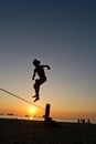 Silhouette of young man balancing on slackline at