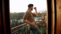 Silhouette of young man dancing ad listening music in wireles headphones stand on hotel room balcony. free lifestyle.