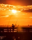 Silhouette of a young man fishing off a pier as the sun sets in the background. Jones Beach, Long Island Royalty Free Stock Photo