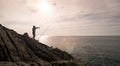 Silhouette of young man fishing on the rocks holding fishing rod with lens flare in phuket Thailand Royalty Free Stock Photo